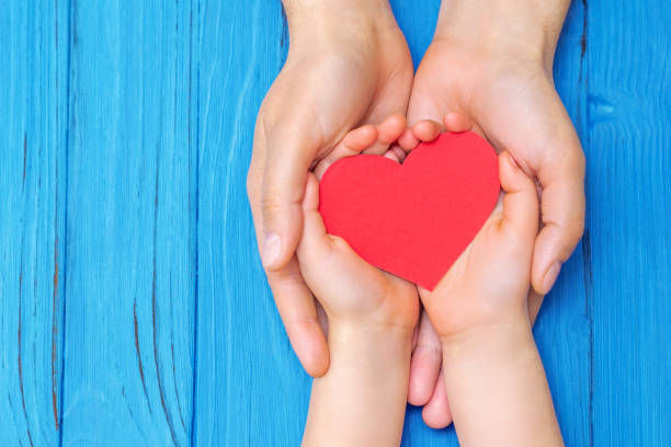 Red heart in child kid and mother hands on old blue wooden table in vintage retro style