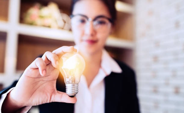 Businesswoman holding light bulb on her hands.