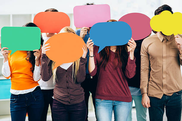 group of people holding colorful speech bubbles on their faces