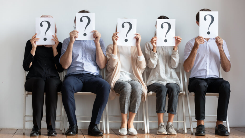 group of people holding a question mark on their faces