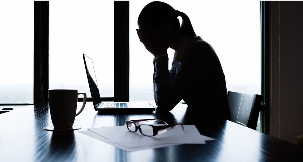 Woman working in the office feeling stress with her hands covering her face.