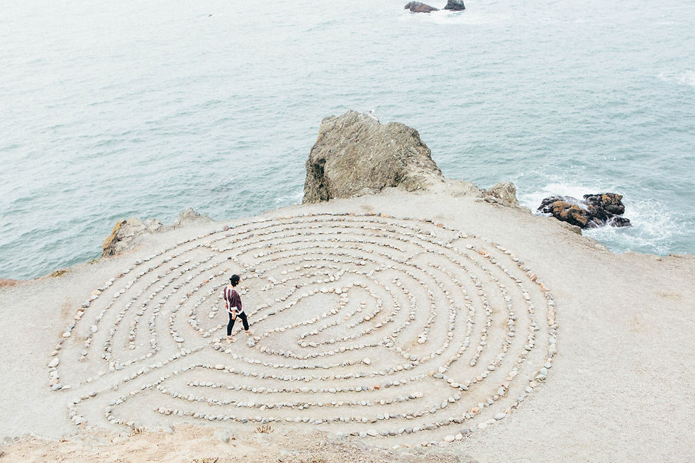 Woman standing in the middle of maze by the sea.