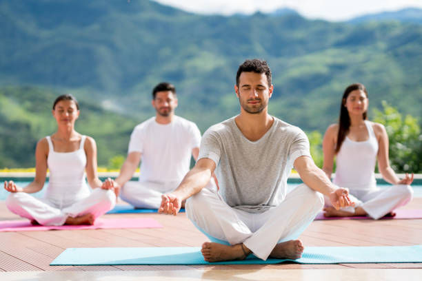 Group of people meditating in a yoga class outdoors and looking peaceful
