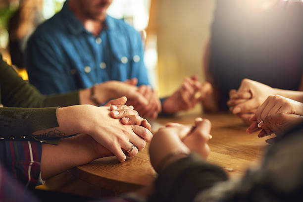 Shot of a group of people holding hands and praying together.