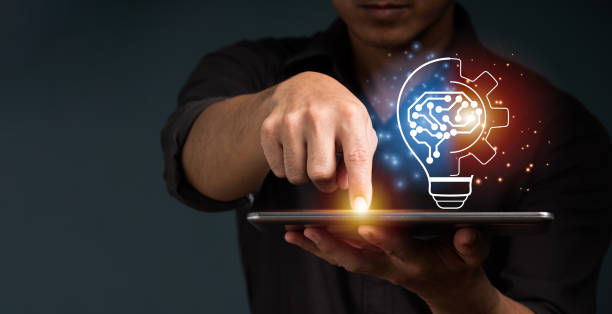 A businessman shows a concept by holding half of a virtual lightbulb and his brain on a digital tablet. 