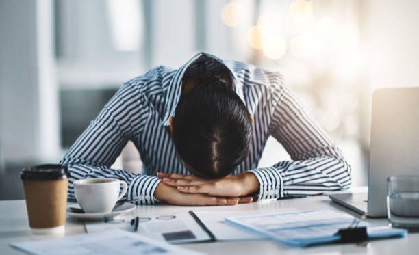 Shot of a young businesswoman lying with her head down on a desk in an office