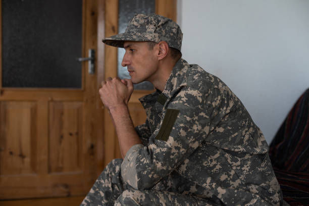 Male veteran sitting and praying. He is wearing military uniform.