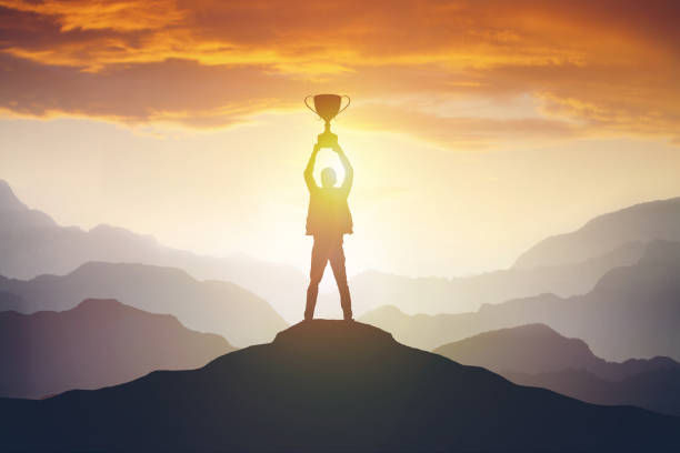 Silhouette of a man holding a trophy at sunset. 
