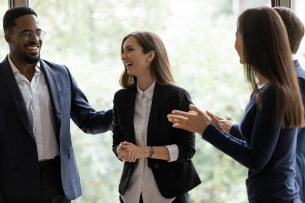 Happy business team applauding coworker success in the office.
