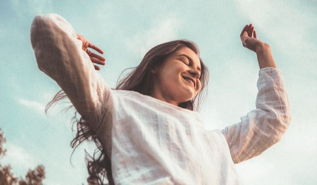 Young woman with arms in the air smiling 
